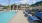  A large swimming pool with blue chairs and a building in the background.