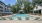  A large swimming pool surrounded by sun loungers and trees.